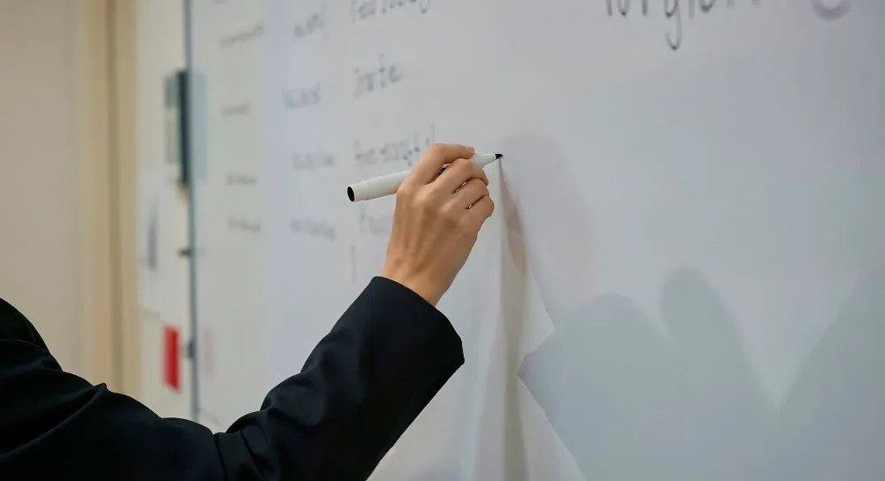 Mão com marcador escrevendo em quadro branco 